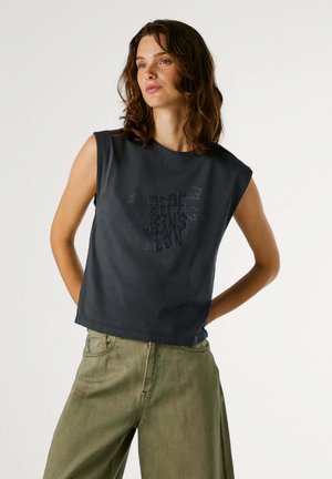 Haut sans manches gris foncé avec un col rond et un design graphique en strass, associé à un pantalon large vert olive.