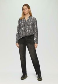 Langmouwige blouse met slangenprint in grijstinten, gecombineerd met zwarte rechte jeans en stevige zwarte laarzen. Soepele stof en ontspannen pasvorm.