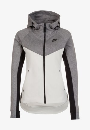 Chaqueta con capucha de Nike con un diseño en bloque de color gris y blanco, cremallera completa y un tejido suave al tacto. Incluye capucha ajustable con cordón.