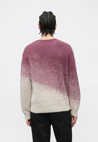 Gradientowy sweter w odcieniach fioletu i kremu o miękkiej, puszystej fakturze. Posiada okrągły dekolt i luźny krój, z widocznym wzorem dzianiny na dole.