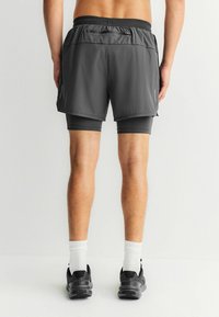 Herre sportsshorts i mørkegrå med et ydre lag og tætsiddende indershorts. Tekstureret stof og elastik i taljen for komfort.