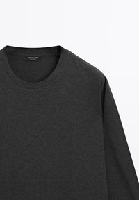 Donkergrijs T-shirt met lange mouwen en ronde hals, gemaakt van zacht stof, toont de bovenkant van het bovenlichaam en de halslijn met zichtbaar merkje aan de binnenkant van de kraag.