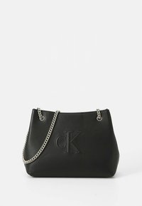 Black leather tote bag with a debossed 'CK' logo, silver chain handles, and a structured shape. Smooth texture and minimal design.