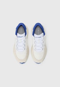 White athletic shoes with blue accents, featuring a mix of smooth and textured materials, lace-up closure, and a cushioned sole.