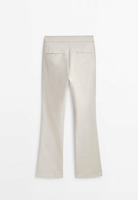 Pantalon beige clair évasé avec une texture lisse, doté de deux poches arrière et d'une ceinture standard. Confectionné pour une silhouette ajustée.