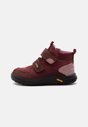 Botte de randonnée enfant bordeaux et rose avec semelle Vibram noire et deux sangles velcro ajustables sur fond blanc.