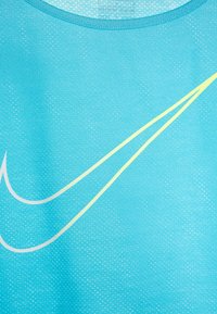 Camiseta deportiva azul claro con una tela suave y transpirable, adornada con un logotipo de swoosh blanco y amarillo. Patrón texturizado sutil en toda la prenda.