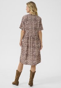 Rochie cu imprimeu de leopard, cu mâneci scurte și talie elastică. Material moale, până la genunchi, asortată cu cizme cowboy din suede maro.