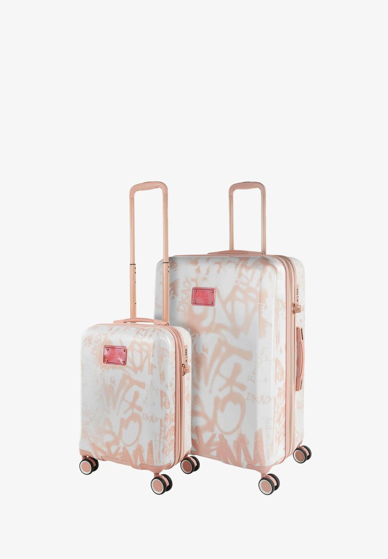 Dos maletas rígidas en blanco con patrones de grafiti rosa, con detalles en rosa dorado, ruedas dobles y asas retráctiles.