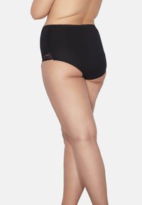 Höga svarta trosor med spetsdetalj på sidan, mjukt material och scallopdetalj längs midjan.