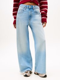 Light blue wide-leg jeans with a faded texture, button closure, and a front pocket. Worn with beige and black sneakers.