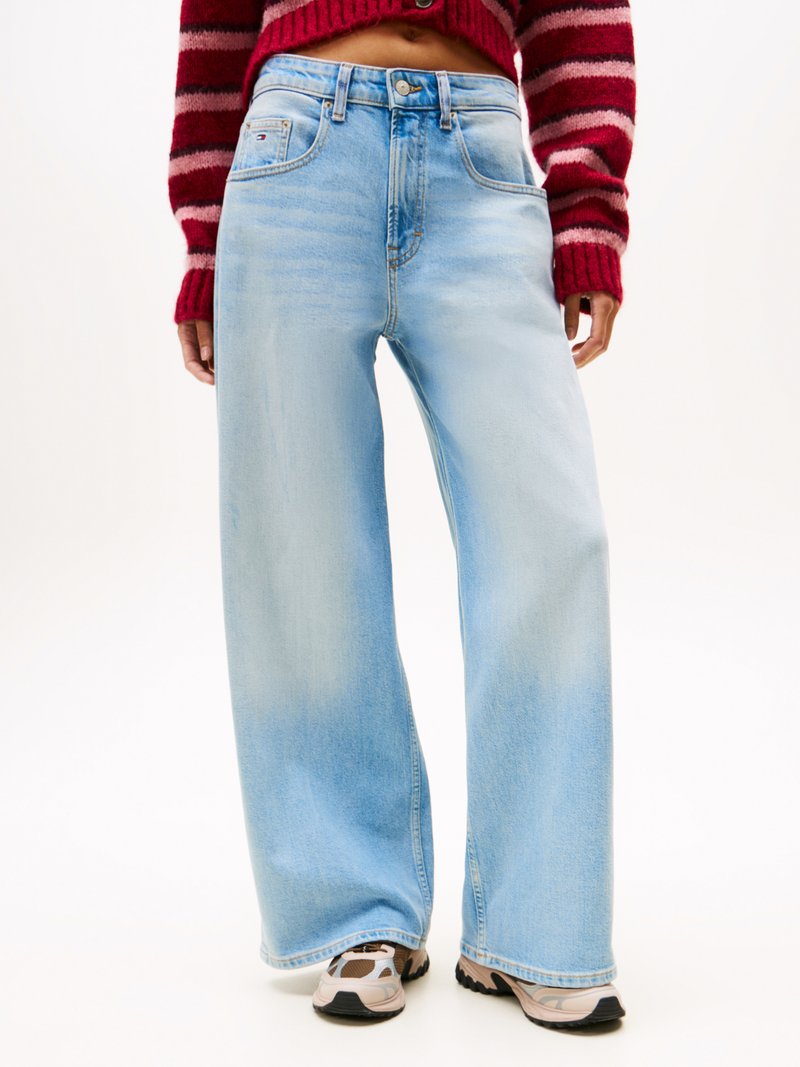 Light blue wide-leg jeans with a faded texture, button closure, and a front pocket. Worn with beige and black sneakers.