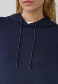 Marineblauer Kapuzenpullover aus weichem Stoff, mit einer Kordel am Hals und einem lockeren Schnitt. Glatte Textur mit einem einfachen Design.