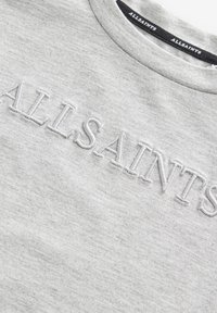 Šedá mikina vyrobená z měkké tkaniny, s vyvýšeným vyšitým nápisem "ALLSAINTS" na hrudi. Design s kulatým výstřihem a texturovaným povrchem.