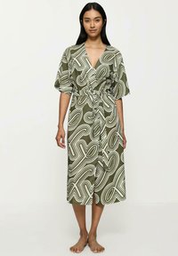 Zielona oliwkowa sukienka w stylu kimono z zabawnym białym abstrakcyjnym wzorem, krótkimi rękawami i wiązanym w pasie, tworzącym zdefiniowaną sylwetkę.