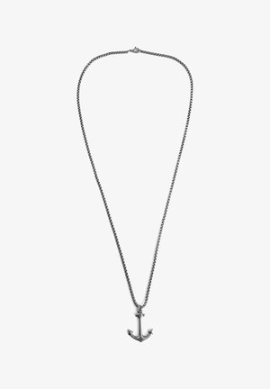 Ezüst tónusú fém láncnyaklánc horgony medállal. A lánc láncszemekből áll, míg a horgony hegyes végekkel van díszítve.