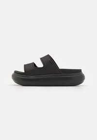 Svart slide sandal med teksturert overdel, åpen tå og doble utskjæringer. Tykk såle gir demping og stabilitet, designet for komfort.