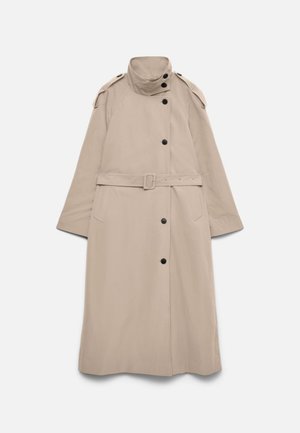 Lang beige trenchcoat med høy krage, svarte knapper, skulderklaffer, belte i midjen og sidelommer, lagt flatt på hvit bakgrunn.
