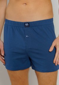 Boxers bleu marine en coton doux, dotés d'une taille élastique, d'une fermeture à bouton à l'avant et d'un tag logo cecaba à la taille.