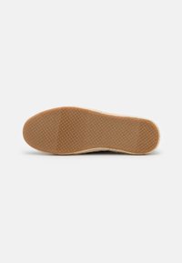 Espadrille-zool met een gestructureerde gumrubberen onderkant, omringd door een geweven jute accent. Lichtbeige kleur met een gladde afwerking.