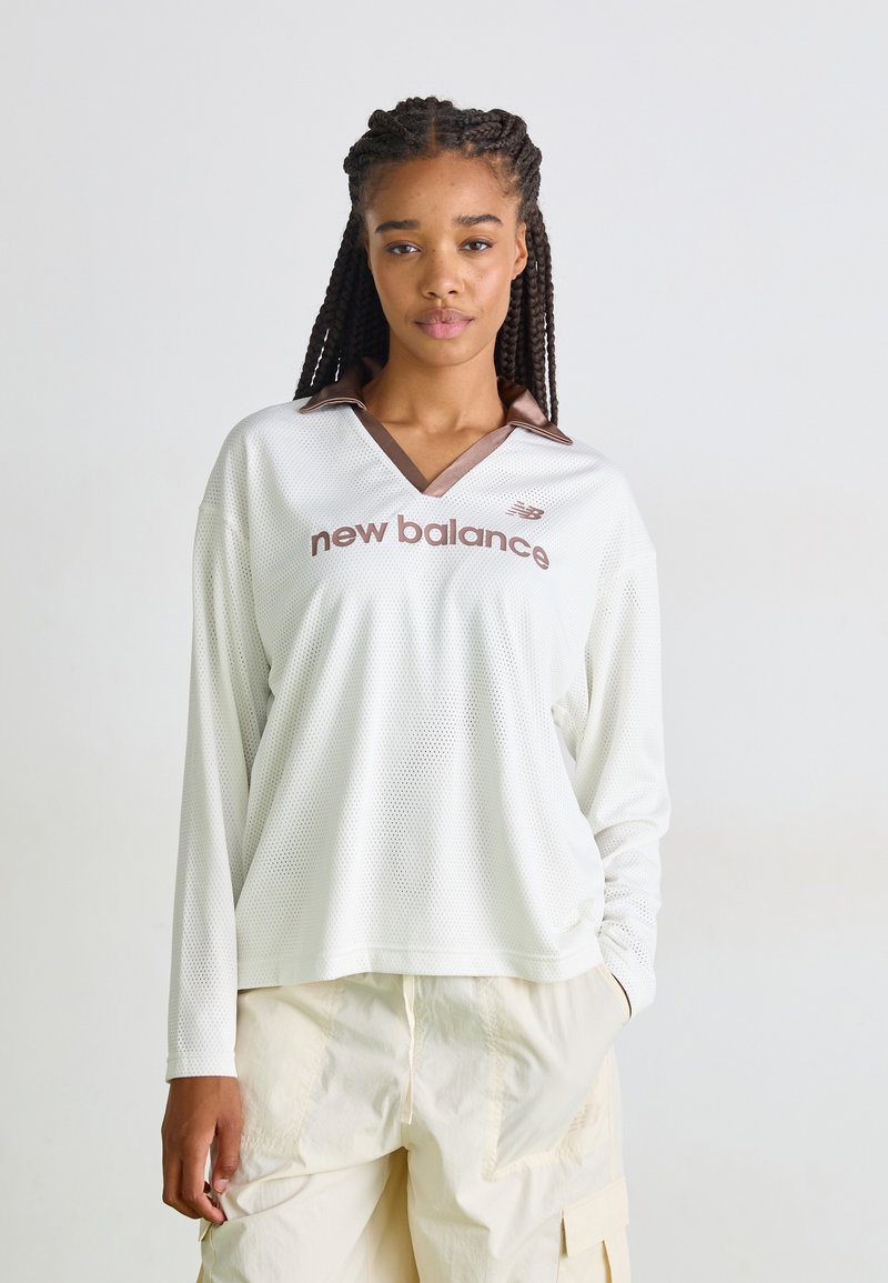 Weißes langärmliges Mesh-Oberteil mit braunem Kragen und "new balance"-Logo auf der Vorderseite. Verfügt über einen lockeren Schnitt und ein V-Ausschnitt-Design.