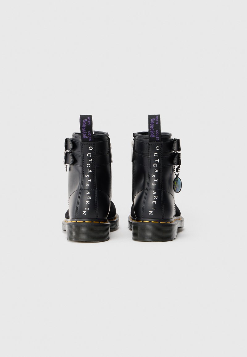 Black leather ankle boots with a rounded toe, silver buckle accents, and purple pull tabs. Features bold white text and stitching details.