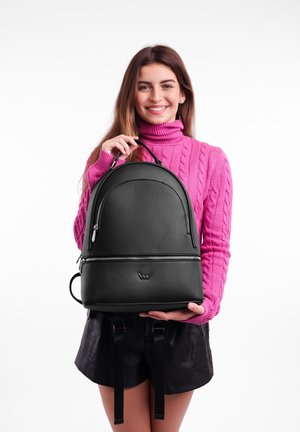 Schwarzer Leder-Rucksack mit runder Form, vorderer Reißverschluss-Tasche und Logo-Akzent. Glatte Textur und verstellbare Träger mit metallischen Beschlägen.