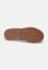 Semelle d'une chaussure présentant une surface texturée en caoutchouc marron avec un motif chevrons et un détail triangulaire central distinct.