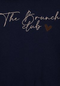 Mornarsko blago z napisom "Brunch klub" v kremastem pisanju, z rjavim srčkom kot poudarkom. Gladka tekstura, sproščen dizajn.