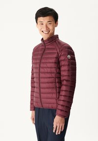 Chaqueta aislante burdeos con cierre de cremallera, que presenta secciones acolchadas horizontales y un cuello alto, fabricada con material ligero.