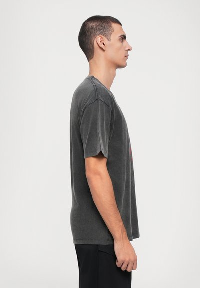 T-shirt de algodão cinza escuro com um corte relaxado, mangas curtas e gola redonda, apresentando detalhes de costura subtis e sem padrões ou elementos adicionais.