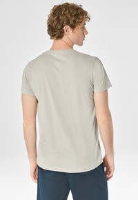 T-shirt grigio chiaro realizzato in tessuto morbido, con collo a giroclassico e maniche corte, orlo dritto e design minimal.