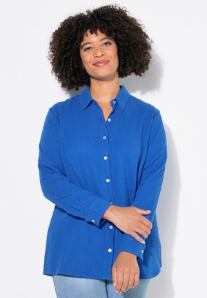 Camicia blu con bottoni in tessuto testurizzato, dotata di colletto, maniche lunghe e bottoni a contrasto; vestibilità comoda con orlo dritto.