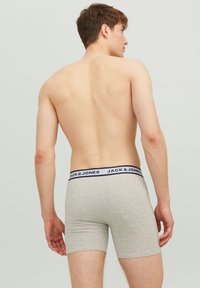 Graue Boxerbriefs aus Baumwolle, mit einem kontrastierenden schwar-weißen Bund, auf dem das Logo "JACK & JONES" steht.