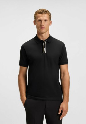 Polo noir en coton avec une coupe ajustée. Doté d'un col zippé avec un bord beige et un logo. Manches courtes et design classique.