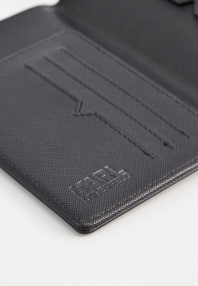 Portefeuille noir texturé avec des emplacements pour cartes, arborant un logo en relief et des lignes épurées. Matériau durable avec un design minimaliste.
