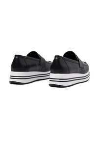 Scarpe in pelle nera senza lacci con punta arrotondata, dotate di una suola intermedia spessa bianca con strisce nere e una consistenza liscia.