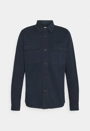 Langærmet mørkeblå skjorte med krave, knapper foran og to brystlommer med knapper.