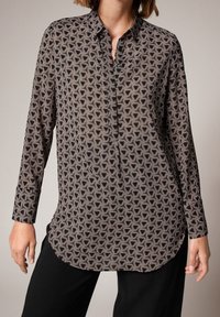 Sort mønstret skjorte med et hexagonalt design i beige og hvid. Lange ærmer, knaplukning og buet kant. Blød stoftekstur.