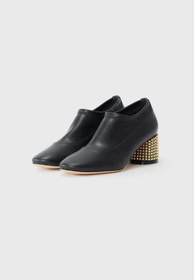 Botine negre din piele cu vârf ascuțit, laterale elastice și toc bloc texturat cu ținte aurii. Finisaj neted cu un design elegant.