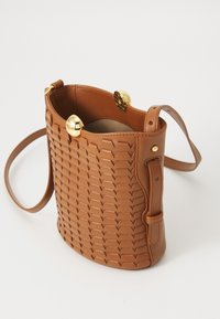 Sac seau en cuir tan avec un motif tissé, accents en métal doré et une bandoulière amovible. S'ouvre par le haut, révélant un intérieur doublé.