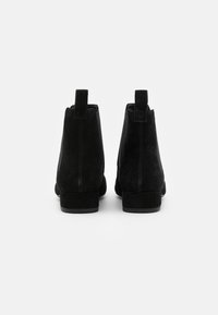 Botas de tobillo de ante negro con tacón bajo, que cuentan con paneles elásticos en los laterales y una lengüeta en la parte posterior para una fácil puesta.