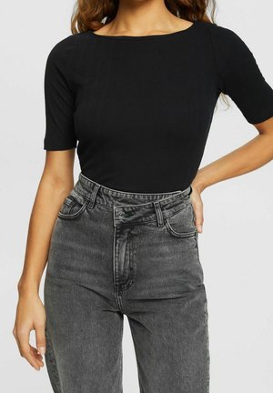 Sort ribbet top med korte ærmer parret med højtaljede grå jeans med subtil falmning og klassisk fem-lomme design.