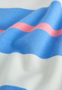 Niebieska, biała i różowa dzianina w paski z widoczną fakturą i miękkimi fałdami.