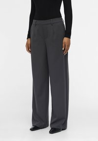 Gray, wide-leg trousers with a smooth fabric texture, featuring a tailored waistband and side pockets, paired with glossy black shoes.