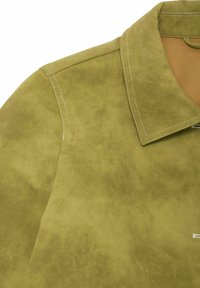 Koszulka z imitacji zamszu w oliwkowym kolorze, z kołnierzem, wyraźnym przeszyciem i widocznym zamkiem błyskawicznym z boku. Gładka tekstura.