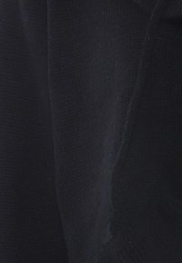 Maglione lavorato a maglia in blu scuro. Presenta un tessuto testurizzato, con una vestibilità ampia e polsini a costine. Design minimalista senza hardware visibile.