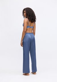 Blauwe satijnen pyjama set met een kant omlijnde beha en wijde broekspijpen, zachte textuur en relaxte pasvorm, met een elastische tailleband.