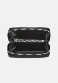 Portafoglio in pelle nera con una chiusura a zip, presenta una texture liscia, hardware della cerniera in argento e due scomparti interni per l'organizzazione.