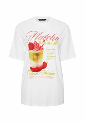 Hvid T-shirt med grafik af en matcha-dessert toppet med jordbær og et rødstribet sugerør, inklusive opskriftstekst og dekorative skrifttyper.